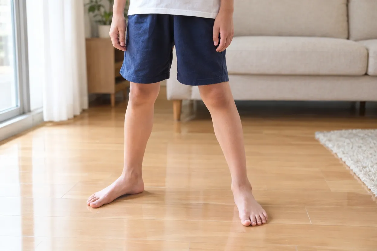足の裏全体で床に立つ子どもの足元